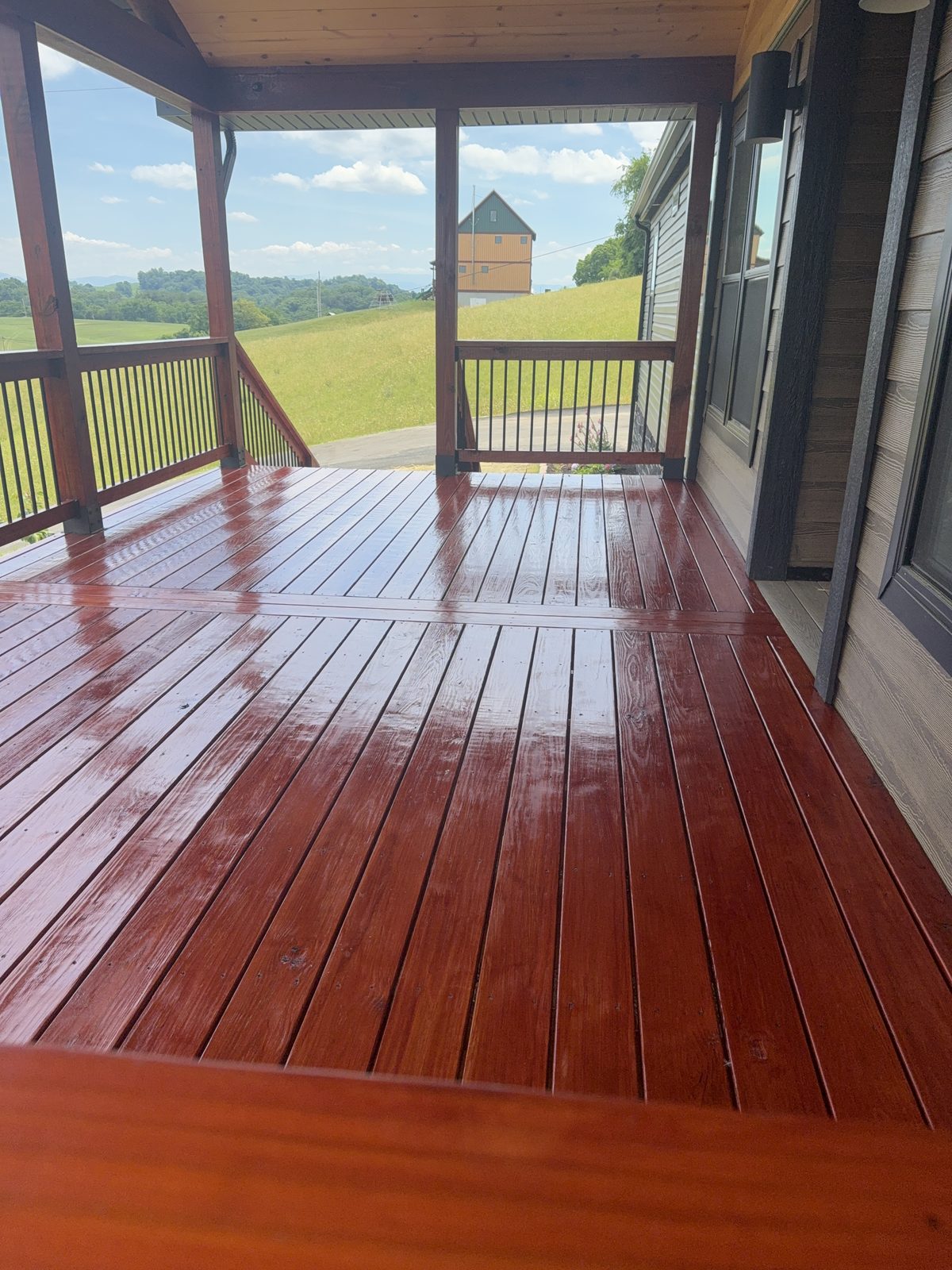 Covered porch deck stained with PPG ProLuxe Mahogany in Piney Flats Tennessee with rolling hills behind