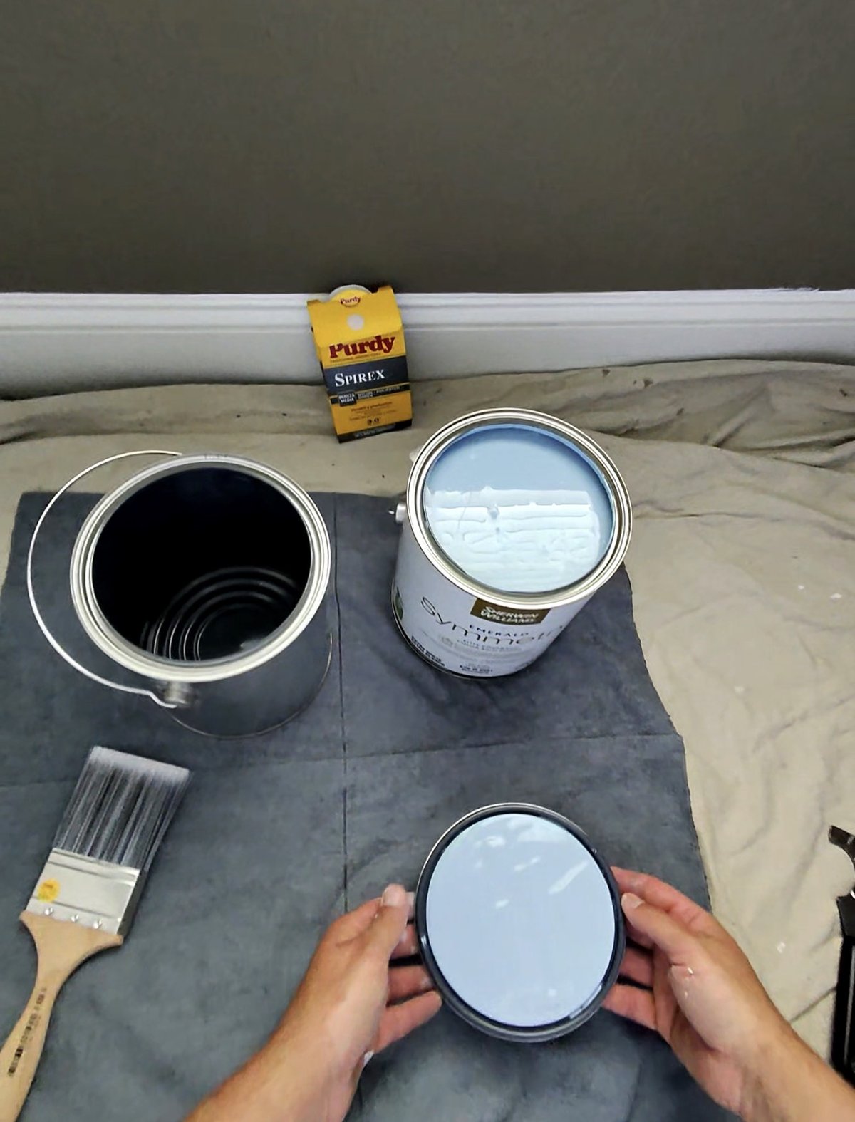 Emerald Symmetry paint can opened next to a new Purdy Spirex 3 inch brush on drop cloths in a bedroom